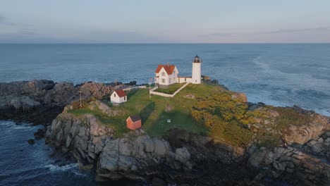 Aerial-Drone-shot-of-York-Beach-Maine-flying-around-Cape-Neddick-Nubble-Lighthouse-at-Sunset