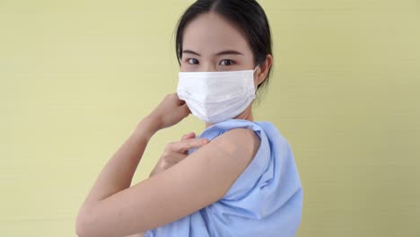 Young-Asian-woman-showing-COVID-19-vaccine-bandage-merrily