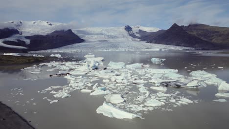 Aerial-flying-over-beautiful-icebergs-floating-in-water,-Jokulsarlon-lake,-natural-climate-snow-landscape,-Iceland