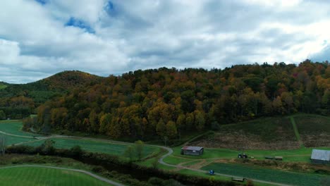 Drone-time-lapse-along-a-windy-road-in-the-countryside-that-runs-along-a-river-and-wraps-around-the-mountains-with-colorful-leaves-during-fall