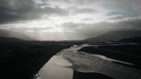 Aerial-thor-valley,-flying-over-glacial-river-flowing-through-black-volcanic-floodplain,-thorsmörk-dramatic-moody-landscape-Iceland