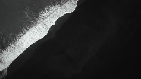 Cinematic-top-down-black-sand-beach-aerial,-waves-crashing-on-volcanic-sand-Iceland,-slow-motion