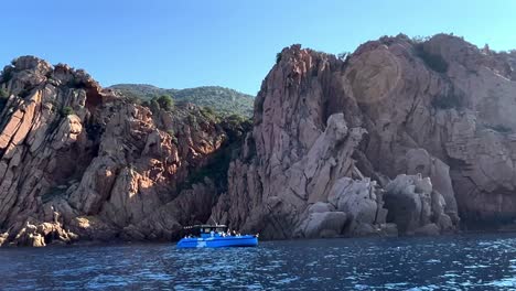 Tour-boat-at-Calanques-de-Piana-volcanic-eroded-rock-formations-in-Corsica-French-island-in-summer-season,-France