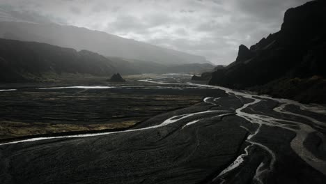 Dramatic-aerial-thor-valley,-glacial-river-flowing-through-black-volcanic-scenery,-thorsmörk-national-park-Iceland