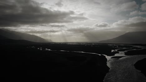 Aerial-flying-up-in-thor-valley,-flying-over-glacial-river-flowing-through-black-volcanic-floodplain,-thorsmörk-dramatic-moody-landscape-Iceland