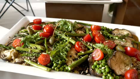 Platter-with-a-salad-consisting-of-eggplant,-peas,-cherry-tomatoes,-asparagus,-and-capers