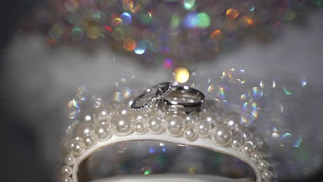Silberne-Eheringe-Auf-Einer-Perlenanzeige-Mit-Glänzendem-Diamanthintergrund