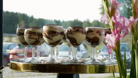 Süßes-Tiramisu-Dessert-In-Eleganten-Gläsern-Inmitten-Von-Blumen