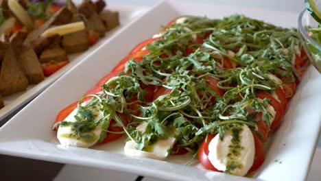 Platter-with-tomatoes,-mozzarella,-arugula,-and-pesto