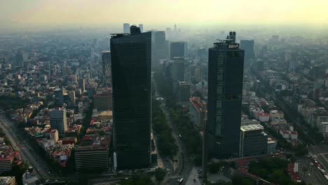 Aerial-hyperlapse-in-orbit-of-the-Reforma-Avenue-in-Mexico-City-CDMX,-with-high-vehicular-traffic-and-a-lot-of-pollution-and-the-Estela-de-Luz