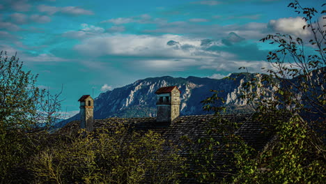 View-over-the-roof-of-a-building,-in-the-background-the-Alps-with-clouds-floating-by