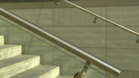 Close-up-of-stainless-steel-handrails-with-glass-panels,-modern-stairway-design-elements