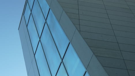 Abstrakter-Winkel-Eines-Modernen-Gebäudes-Mit-Einer-Geometrischen-Glasfassade-Vor-Einem-Klaren-Himmel