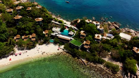 Slowly-pulling-in-on-a-aerial-drone-shot-of-Sa-Daeng-beach-with-its-white-sandy-beaches,-crystal-clear-blue-waters,-and-accommodations-in-the-island-of-Koh-Tao-in-Surat-Thani-province-in-Thailand