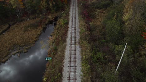 Aerial-tilt-up-of-old-railway-track-near-autumn-forest-and-electric-line