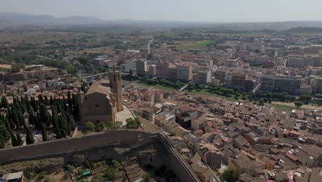 Eine-Faszinierende-Kreisförmige-Drohnenansicht-Fängt-Die-Pracht-Der-Katholischen-Kirche-Santa-Maria-De-Balaguer-In-Lleida,-Spanien,-Ein,-Beleuchtet-Von-Der-Nachmittagssonne