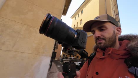 Man-walking-along-city-street-of-Verona-while-holding-professional-camera-mounted-on-stabilizing-gimbal-DJI-RS3-Mini