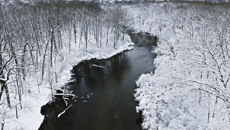 As-the-drone-glides-along-the-meandering-course-of-the-river,-it-reveals-the-subtle-movements-beneath-the-icy-surface