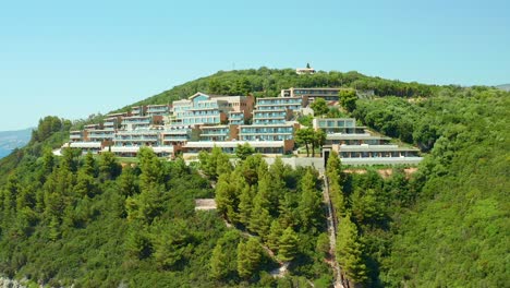 Aerial-dolly-shot-of-Elix-Mar-Bella-Luxury-hotel-on-Forested-Hillside-Above-Karavostasi-Beach,-Greece