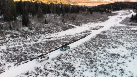 Aerial-orbit-with-pan-reveal-of-two-cars-with-Christmas-trees-in-Idaho-National-Forest-during-a-winter-sunset