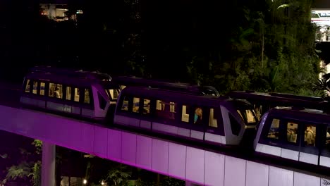 Skytrain's-Passing-Each-Other-Inside-Jewel-Changi-Airport-Being-Illuminated-By-Purple-Light-From-Waterfall