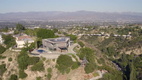 4K-aerial-of-modern-hilltop-home-with-full-view-of-the-San-Fernando-Valley-in-the-background