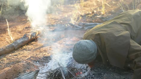 A-bushman-blows-on-a-campfire-to-get-it-started-in-the-Australian-outback