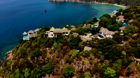 A-slow-orbit-aerial-drone-shot-of-the-Sai-Daeng-beach-cove,-showing-the-luxurious-villas,-white-sandy-coastline,-and-the-crystal-blue-turquoise-waters-of-the-Andaman-Sea,-in-Koh-Tao-island,-Thailand