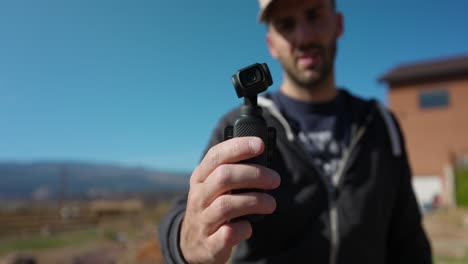 Close-up-view-of-DJI-Osmo-Pocket-3-being-held-and-operated-by-a-man-outdoors-for-vlog
