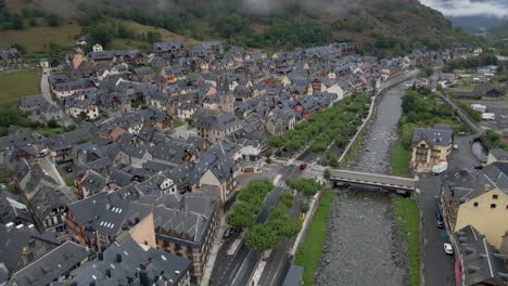 The-drone-gracefully-descends-to-a-tranquil-riverbed-in-a-picturesque-Spanish-town-nestled-within-the-stunning-Pyrenees-mountains