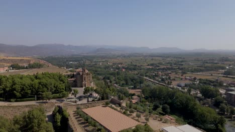 A-captivating-far-distance-drone-circular-shot-captures-the-beauty-of-the-Catholic-Church-Santa-Maria-de-Balaguer-in-Lleida,-Spain,-as-it-gleams-in-the-warm-afternoon-sun