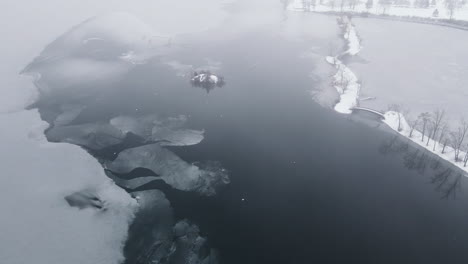 Drohnenaufnahme-Einer-Winterszene-Mit-Vögeln-Auf-Der-Vereisten-Oberfläche-Eines-Zugefrorenen-Flusses