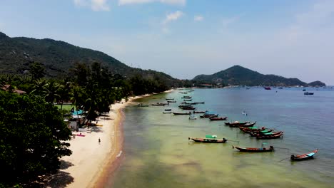 A-pedestal-aerial-drone-shot-of-Sairee-beach-showing-a-number-of-fishing-boats,-some-fishermen,-and-tourists-at-the-beachfront-located-in-Koh-Tao-island-in-Surat-Thani-province,-Thailand