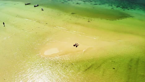 Hovering-above-for-an-orbital-aerial-drone-shot-of-some-tourists-who-are-sunbathing-on-a-sand-bar-in-Choeng-Mon-beach,-Koh-Tao-island-in-Surat-Thani-province,-Thailand