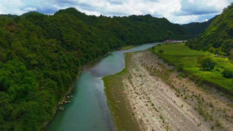 Aerial-over-emerald-waters-of-Daywan-river-with-tropical-forest-along-the-river-bank