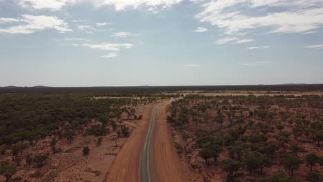 Luftaufnahme-Einer-Leeren-Straße-Im-Australischen-Outback,-Umgeben-Von-Bäumen-Und-Büschen-Mit-Roter-Erde