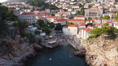 Local-people-swimming-and-relaxing-on-rocky-sulic-beach-in-Dubrovnik-city,-Aerial