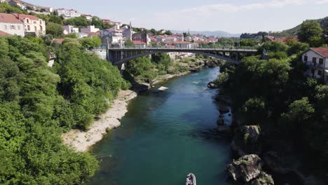 Aerial-view-towards-Lučki-most-Mostar-city-bridge-and-stunning-scenic-blue-water-of-Neretva-river,-Bosnia-and-Herzegovina