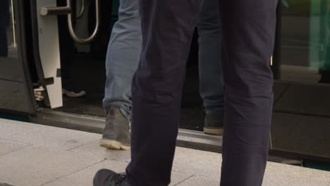Slo-mo-detail:-Public-legs,-feet-walk-onto-commuter-train-at-station