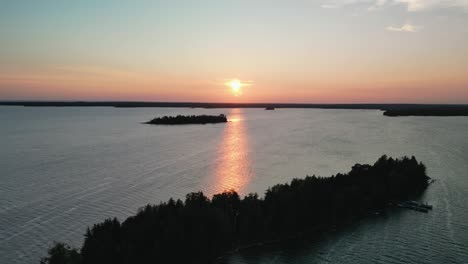 Aerial-island-view-of-pink-summer-sunset-reflecting-on-lake-water-in-Les-Cheneaux-Islands,-Michigan