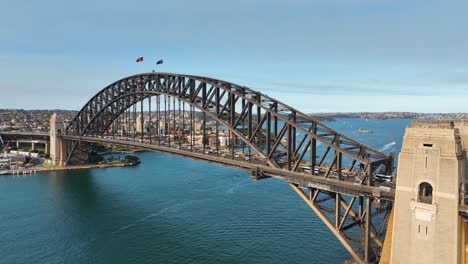 Cinematic-Aerial-Shot-Panning-From-Sydney-Harbour-Bridge,-Underneath-Bridge-To-Reveal-Sydney-Opera-House,-Sydney-Landmark-At-Sunset,-Australia