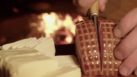 Thick-ham-and-cheese-slices-prepared-on-cutting-board-by-hot-camp-fire
