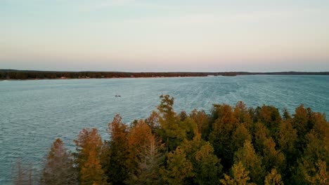 Luftaufnahme-über-Wechselnde-Blätter-Am-Seeufer-Mit-Kanuüberquerung-Des-Sees,-Les-Cheneaux-Islands,-Michigan