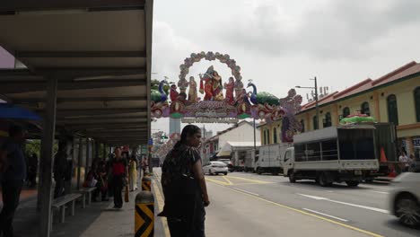 Traffic-Seen-Along-Serangoon-Road-In-Little-India,-Singapore-Beside-Bus-Stop-With-Diwali-Decorations-Seen-In-Background