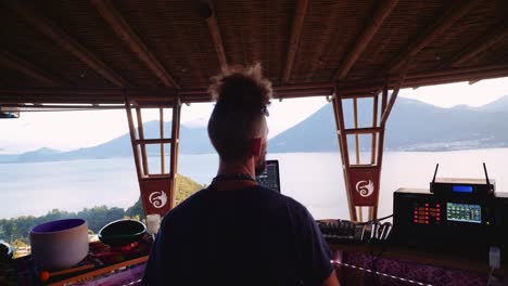 Epic-forward-travelling-shot-of-DJ-at-ecstatic-transe-electronic-music-festival-on-platform-overlooking-lake-Atitlan-Guatemala