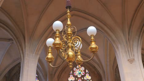 Low-angle-shot-of-a-chandelier-hanging-from-ceiling-inside-roman-catholic-church-Saint-Germain-l'Auxerrois-in-Paris,-France