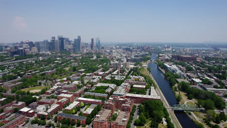 Drone-shot-following-the-Lachine-Canal,-toward-the-skyline,-summer-in-Montreal