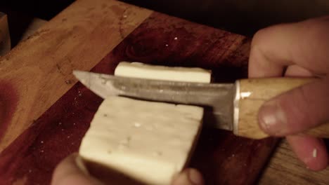 Narrow-focus-close-up-view:-Forged-knife-cuts-block-of-Halloumi-cheese