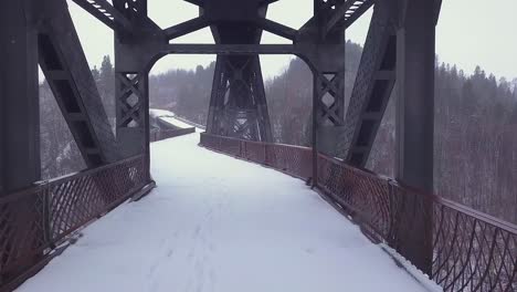 Monochrome-winter-POV-along-abandoned-bridge-deck-below-rail-crossing