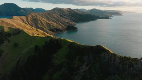 Beautiful-sunlight-over-craggy-slopes-of-Te-Aumiti-French-Pass-with-views-of-serene,-calm-ocean-water-in-Marlborough-Sounds,-South-Island-of-New-Zealand-Aotearoa